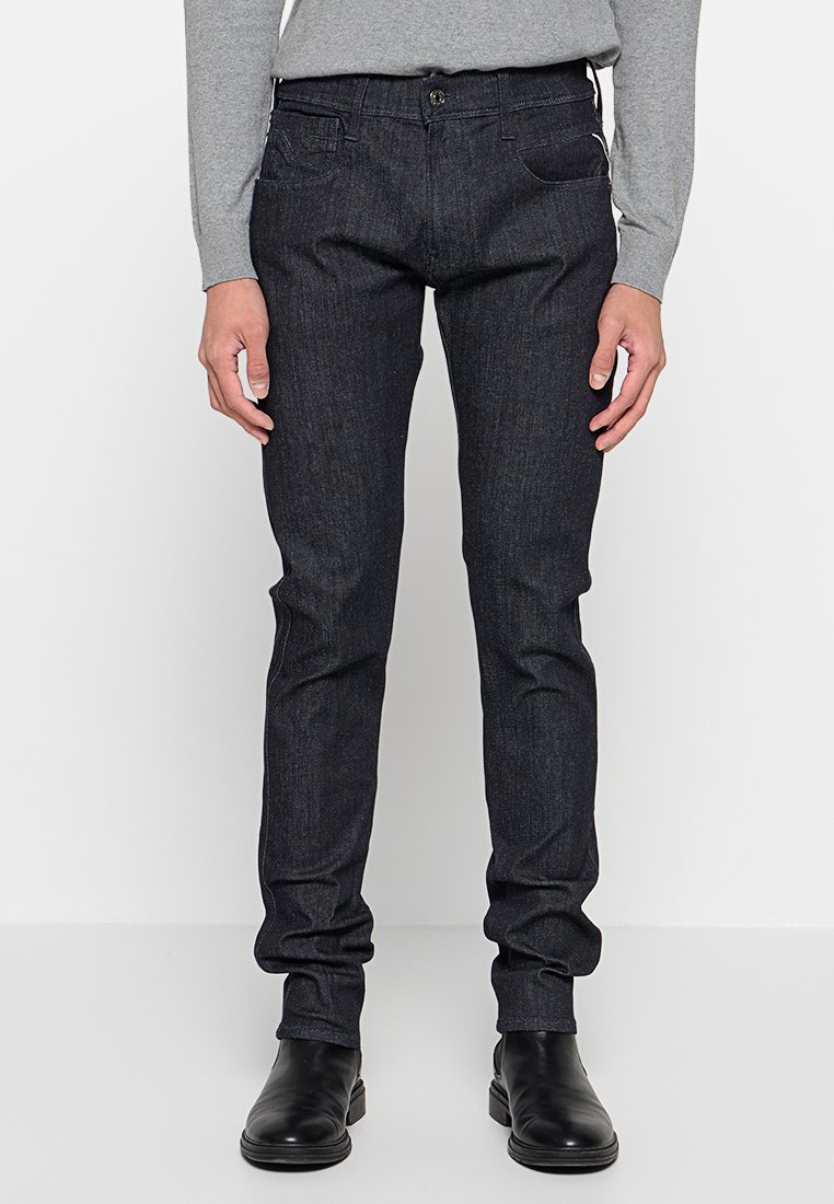 Dunkelblaue Denim-Jeans mit schmaler Passform, ausgestattet mit einem vorderen Knopfverschluss, fünf Taschen und einer glatten, leicht strukturierten Oberfläche.