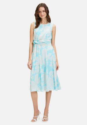 Hellblaues, ärmelloses Kleid mit weißen Blumenmuster, geknotetem Taillendetail und fließendem Rock. Glattem Stoff mit weicher Textur.