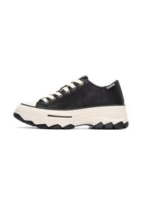 Zapatilla de cuero negra con cordones blancos, suela gruesa beige, acentos de goma negra y una superficie texturizada. Presenta un logo en el talón.