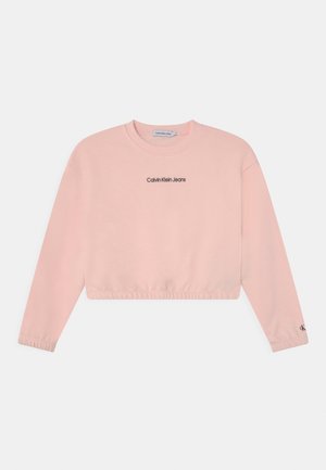 Sudadera corta rosa con mangas largas, con cuello y puños acanalados, y el logo "Calvin Klein Jeans" en negro en la parte delantera.