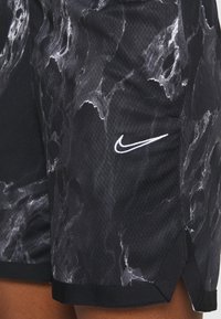 Nike shorts in black with a marble pattern. Made of textured fabric with a white logo. Features a side vent for ease of movement.