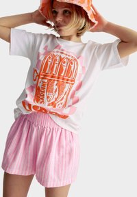 Witte t-shirt met een oranje sardine graphic, gecombineerd met lichtroze gestreepte shorts met een elastische tailleband. Heeft een casual pasvorm.