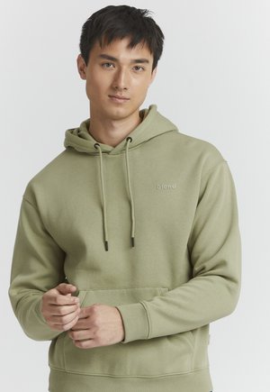 Khaki-grüner Hoodie mit einer Kapuze mit Kordelzug, Kängurutasche und Logo-Detail auf der Brust. Hergestellt aus weichem, strukturiertem Stoff.