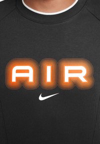 Felpa nera con grande grafica "AIR" in arancione e bianco con dettagli delineati. Piccolo logo Swoosh Nike bianco in basso.