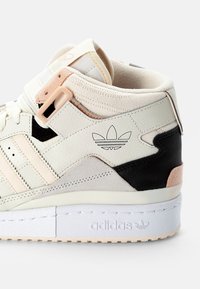 Höga sneakers i vitt, svart och persikofärgat läder, med en texturerad yta, sydda ränder och en logotypdetalj på sidan.