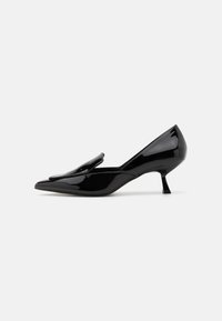 Black patent leather mid-heel shoes with a pointed toe and a folded accent on the upper. Slim heel design, smooth texture.