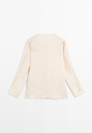Langærmet top i lys beige, let krøllet stof, med rund udskæring og lige pasform. Minimalistisk design, uden synligt hardware eller accenter.
