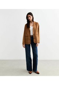 Bordeaux suède blazer met ingegraveerde revers, twee voorkantenzakken en drie knopen, gecombineerd met hoge taille donkerblauwe denim flared jeans.