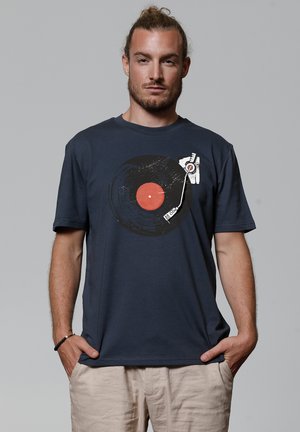 Navy blauwe katoenen t-shirt met een afbeelding van een vinylplaat met een rode center en een stylus, korte mouwen en een losse pasvorm.