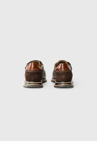 Zapatos de cuero y ante marrón con un acabado suave, que presentan un acento marrón contrastante en el talón y una suela de goma gruesa y con patrón.