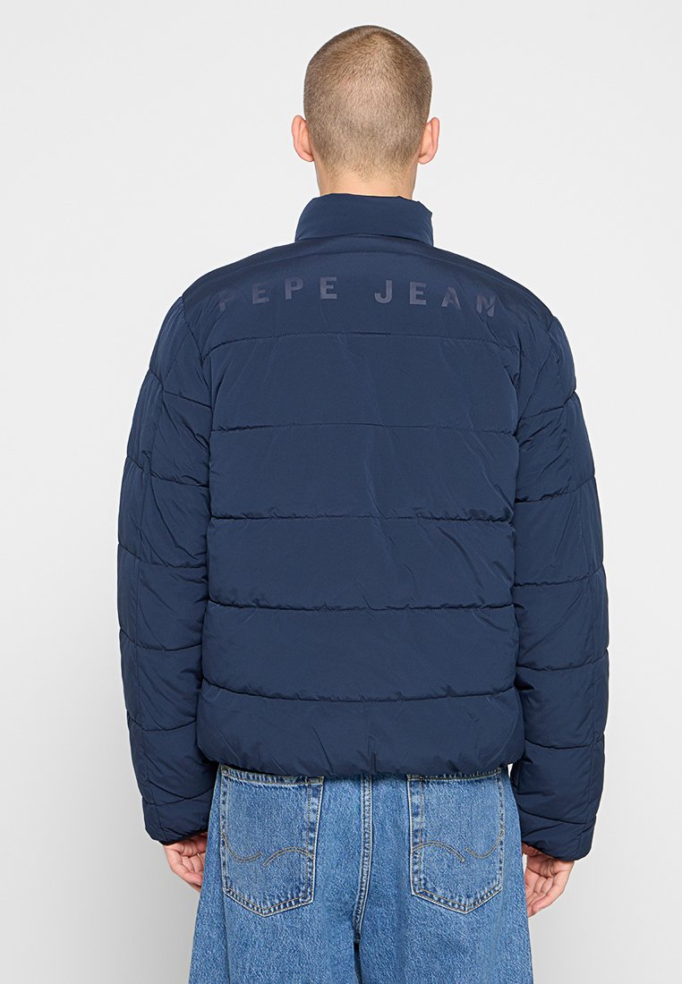 Veste matelassée bleu marine avec un design matelassé, dotée d'un col montant et du texte "PEPE JEAN" dans le dos. Texture lisse, coupe décontractée.