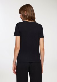 T-shirt in cotone nero con maniche corte e scollatura rotonda, caratterizzato da una vestibilità normale e una consistenza liscia e morbida. Nessun motivo o dettaglio visibile.