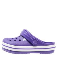Zoccoli Crocs viola con punta chiusa, fori per la ventilazione, cinturino regolabile e suola a strisce bianche. Realizzati in materiale in schiuma leggero.