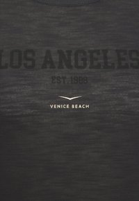 Black T-shirt made of lightweight fabric featuring "LOS ANGELES" in bold black, "EST. 1980" and "VENICE BEACH" in smaller white text below.