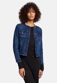 Mørkeblå denimjakke med en kortet design, flosset kant og knaplukning foran. Har to brystlommer og kravefri udskæring.