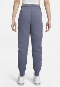 Katoenen/polyester joggers in slategrijs met een geribde tailleband, taps toelopend ontwerp en zijzakken. Gecombineerd met witte sportschoenen.