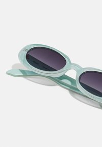 Pora pailgintų, mėtų žalios spalvos akinių nuo saulės su tamsiais lęšiais, turinčių lygią plastikinę rėmelį ir elegantiškas, suapvalintas šventyklų dalis.