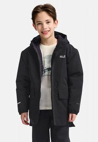Black waterproof jacket with zip and hood, featuring gray accents. Worn over a light shirt, displayed on a child in a neutral background.