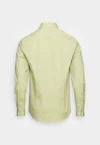 Camicia gialla chiaro a maniche lunghe in cotone, con colletto appuntito, polsini con bottoni e tessuto liscio. Vista posteriore che mostra una vestibilità sagomata.