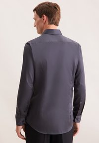 Heren langarmshirt in donkergrijs, van soepele stof. Voorzien van een klassieke kraag, knoopmansetten en een afgeronde zoom voor een getailleerde pasvorm.
