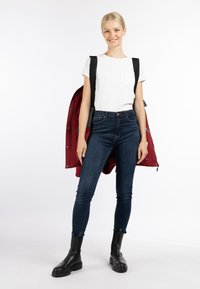 Hvid kortærmet t-shirt med lomme, mørkeblå skinny jeans, rød jakke hængende over skulderen, og sorte ankelstøvler med kraftige såler.