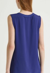 Top senza maniche di un blu vivace, realizzato in tessuto liscio. Presenta un collo rotondo e una cucitura sottile lungo le spalle e l'orlo.