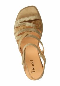 Złote sandały na obcasie typu wedge z paskami, z nakładającymi się paskami w górnej części i wyściełaną wkładką. Projekt z rozszerzonym palcem.