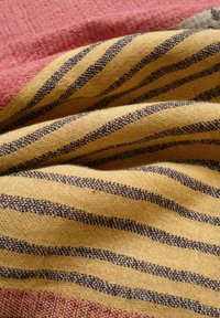 Textile with red and yellow fabric. Yellow features black stripes, and the surface has a textured weave. Pleated and layered appearance.