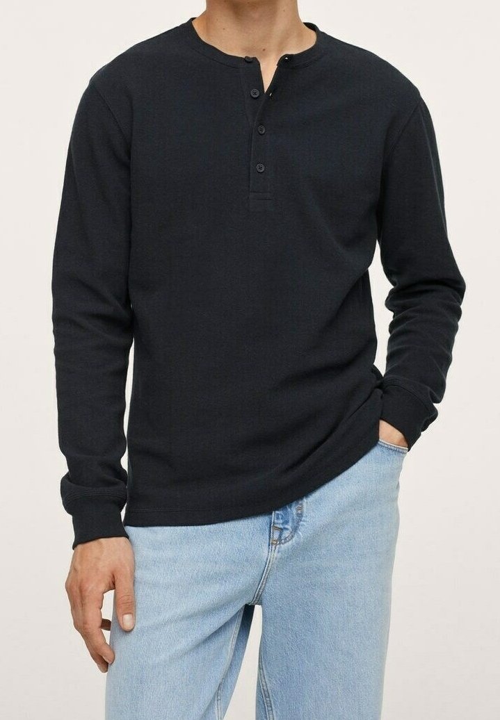 Black long-sleeve henley shirt with a buttoned neck placket, made of soft fabric; paired with light blue denim jeans.