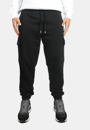 Pantaloni cargo neri in felpa con cintura elastica e cordino, dotati di tasche laterali e polsini a costine. Abbinali a scarpe sportive grigie.
