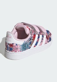 Roza superga z rožnatimi vzorci, ki vključujejo modre, rdeče in vijolične poudarke. Zapirala na ježka, bel podplat in oblazinjen notranji del za udobje.