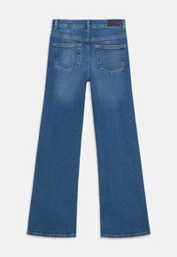 Blaue Jeans mit weitem Bein, zwei Gesäßtaschen, Gürtelschlaufen und einem schwarzen Lederpatch am Bund.