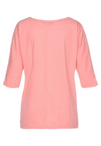 Light pink, loose-fitting t-shirt with a wide neck and three-quarter sleeves. Soft cotton fabric, featuring a straight hem and side slits.