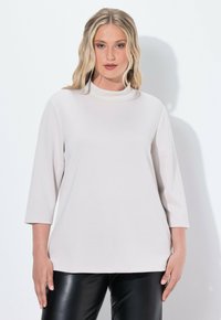 Maglione a collo alto beige chiaro con maniche a tre quarti, realizzato in un tessuto morbido. Presenta una vestibilità comoda e un design minimale, senza fantasie.