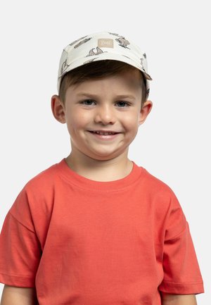 Joven sonriente con gorra blanca estampada con el logo "Buff" y camiseta naranja coral sobre un fondo claro liso.
