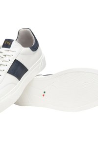 Sneakers bianchi in pelle con dettagli blu navy, suola in gomma piatta, suola testurizzata e logo dorato sulla linguetta. Caratterizzati da un design basso.