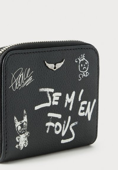 Черен кожен портфейл с бял текст "JE M'EN FOUS," драскулки, тъжно лице, казващо "CUTE SAD," и малка метална украса във формата на крило.