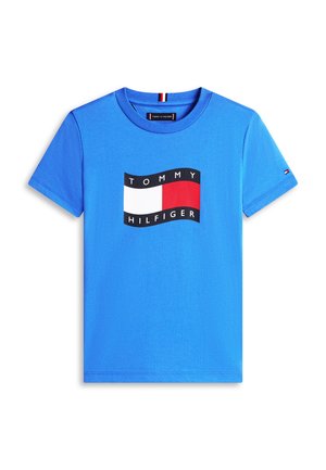 Blue short-sleeve t-shirt with a round neck and a central rectangular logo in white, red, and black with the text "Tommy Hilfiger."