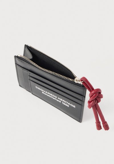 Μαύρη δερμάτινη θήκη για κάρτες με φερμουάρ, τρεις θήκες για κάρτες, λευκό κείμενο "DSQUARED2 HERITAGE Established 1995" και κόκκινη δερμάτινη θηλιά με κόμπο.