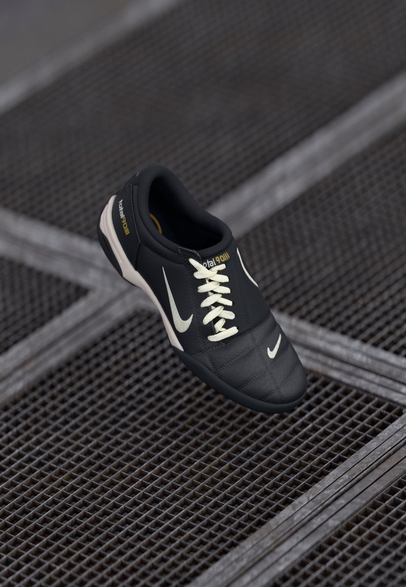 Baskets Nike noires avec lacets blancs et logo, flottant au-dessus d’un sol en grille métallique sombre.