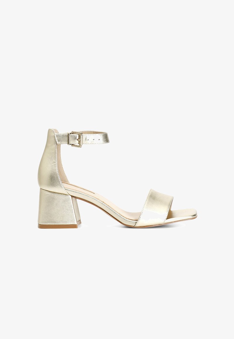 Sandal de tacón dorado metalizado con punta abierta, una sola tirante cruzando el pie y una correa ajustable en el tobillo. Diseño de tacón cuadrado.