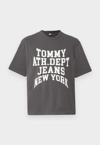 Sivá bavlnená tričko s krátkymi rukávmi, s výrazným bielym textom: "TOMMY ATH.DEPT JEANS NEW YORK" v zakrivenom dizajne.