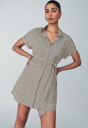 Abito a maniche corte color crema con motivo a zigzag nero, dotato di colletto e cintura in vita. Tessuto leggero con vestibilità comoda.