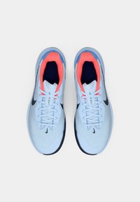 Pantofi sport de culoare albastru deschis, cu un superior din plasă texturată, talpă de culoare albastru închis și accente coral strălucitoare în guler și șireturi.