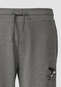 Grijze joggingsbroek met een touwtjesriem en een klein Snoopy-personage dat een rode winterhoed draagt, nabij het rechterzak.