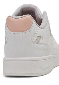 Vit sneaker med en texturerad gummisula, slät yta, rosa hälaccent och sidoperforeringar för andningsförmåga. Guld logodetalj.