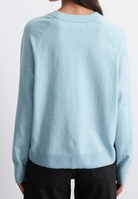 Vaalean sininen neulepusero, jossa on rento istuvuus, pehmeä rakenne, rosoinen helma ja hihansuut sekä raglanhiha. Ei näkyviä kuvioita tai yksityiskohtia.