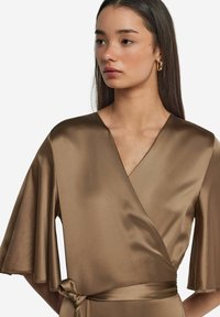 Braunes Wickelkleid mit tiefem V-Ausschnitt und weiten Ärmeln, aus glattem, glänzendem Stoff. Mit einem passenden Gürtel in der Taille abgerundet.