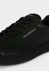 Μαύρο δερμάτινο sneaker με χαμηλό πάνω μέρος, μαύρα κορδόνια και σήμανση "KARL LAGERFELD" στο πλάι.