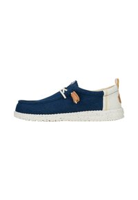 Scarpa slip-on in tessuto blu marina con suola screziata bianca, lacci bianchi e dettagli in marrone chiaro, caratterizzata da cuciture sul retro e etichette laterali.